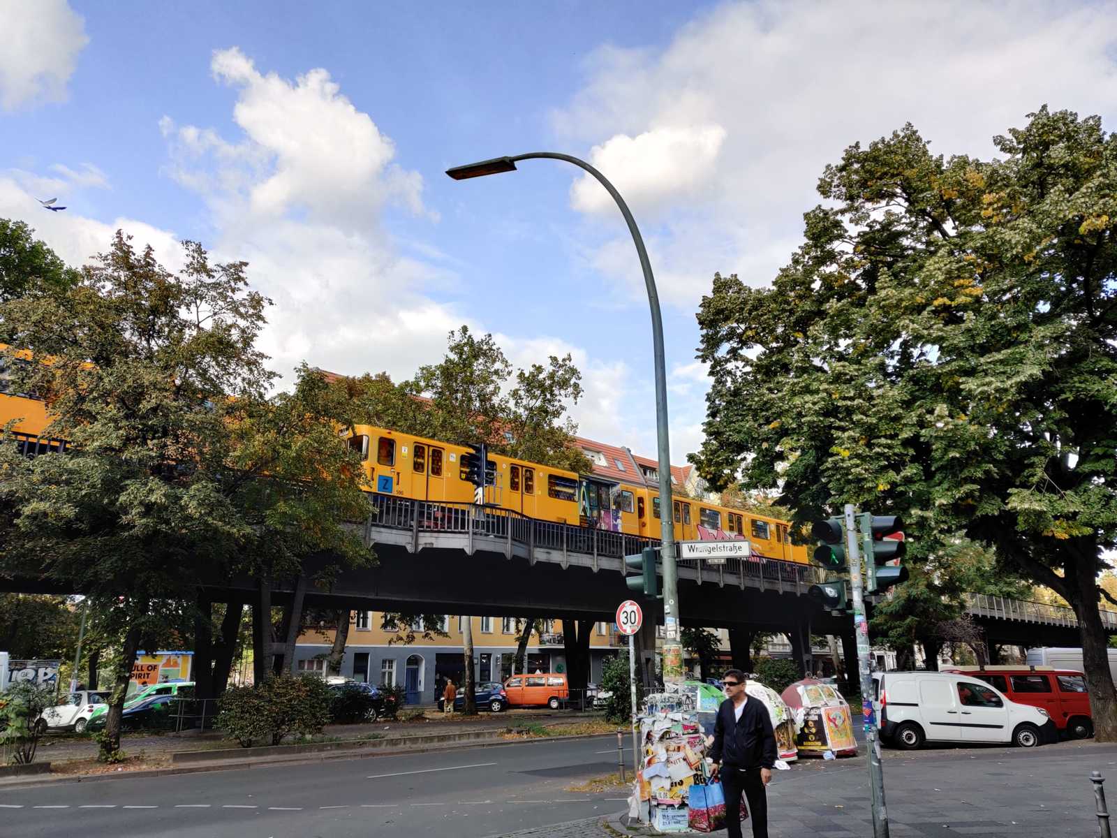 train jaune BVG passant sur un pont. Homme attends rue. Été, ciel bleu, un peu de nuages. Berlin Wrangelkiez Germany