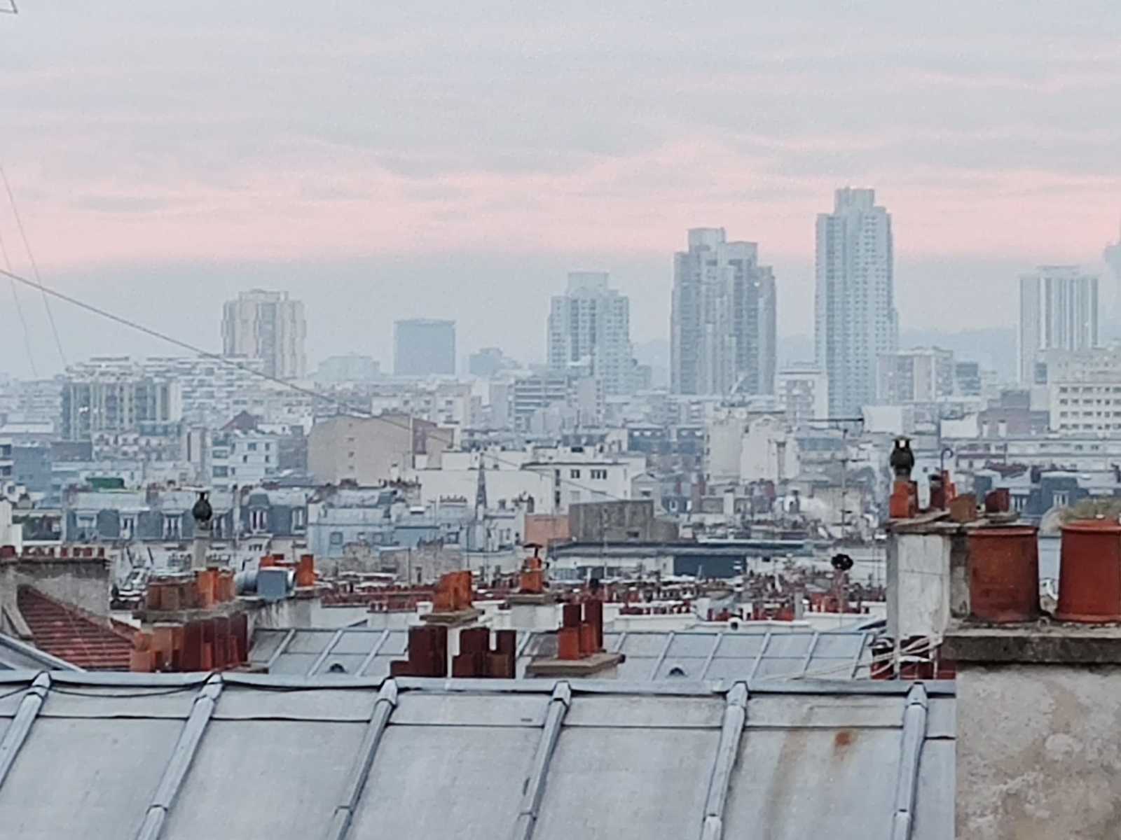 Sicht über Häuserdächer Paris Montmartre Sacre Coeur Miethaie Marchands de sommeils. Smog am Horizont