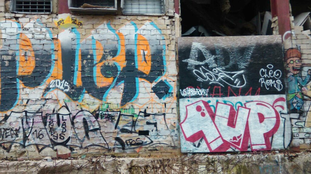 1UP Graffiti in Berlin, Hauswand, kleines graffito, weiße fill-ins mit roten outlines und eckigen Buchstaben urbane Kultur Stadtkultur urbanität 