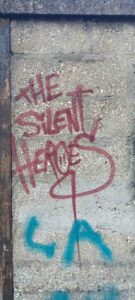 Dijon graffiti tagg "The silent heroes" on old soaking wall in red writing. vandalism urban culture subculture